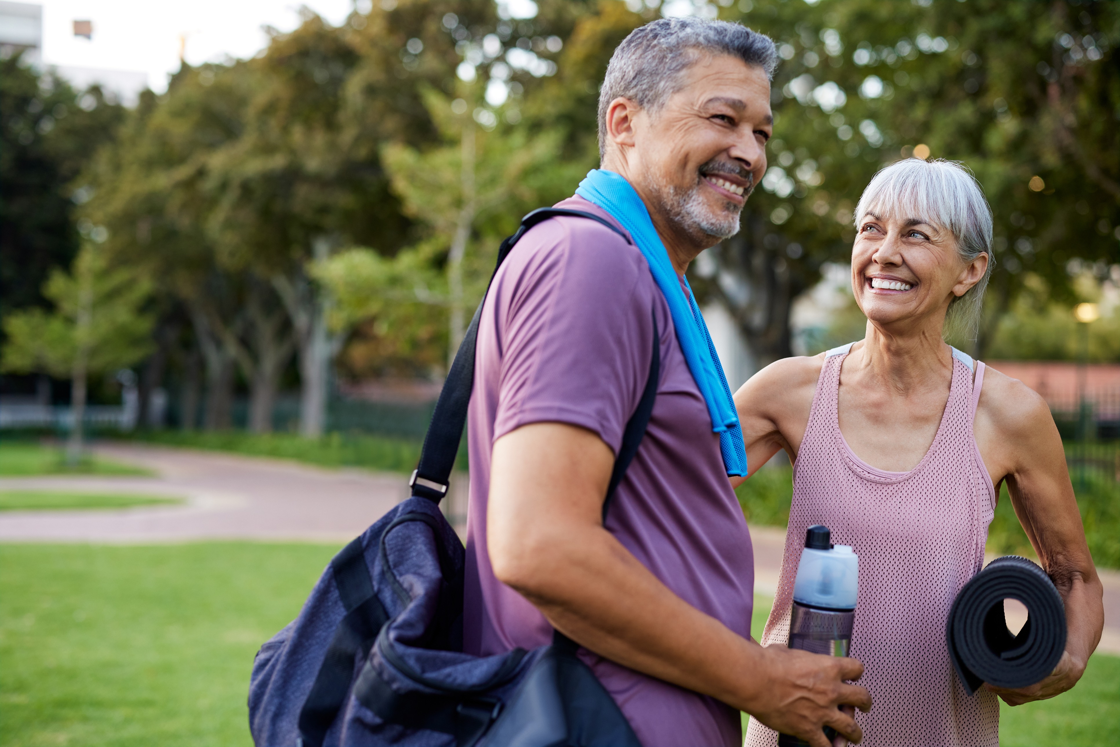 An active, smiling older couple in workout gear outdoors, embodying the energy and vitality of healthy aging